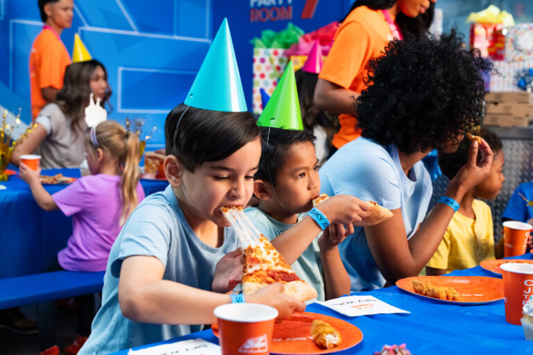 Two little boys eating pizza at a sky zone birthday party