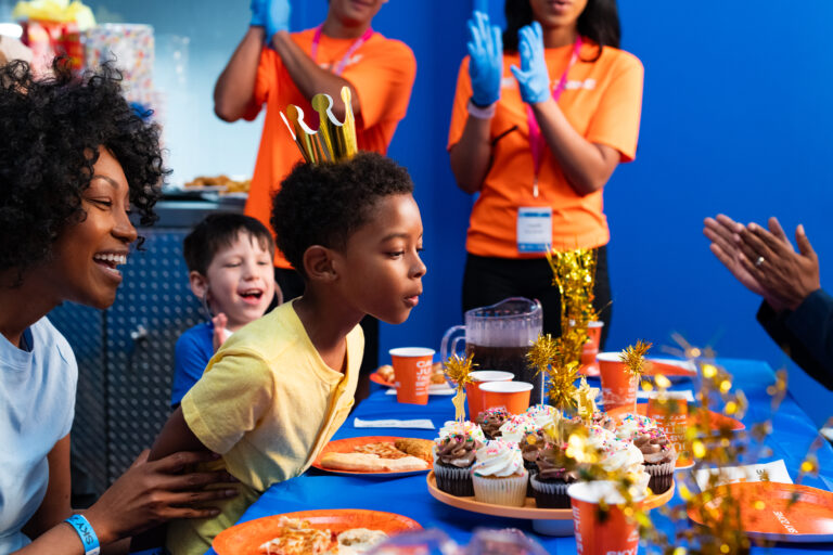 Little boy blowing out candles on his sky zone birthday cake